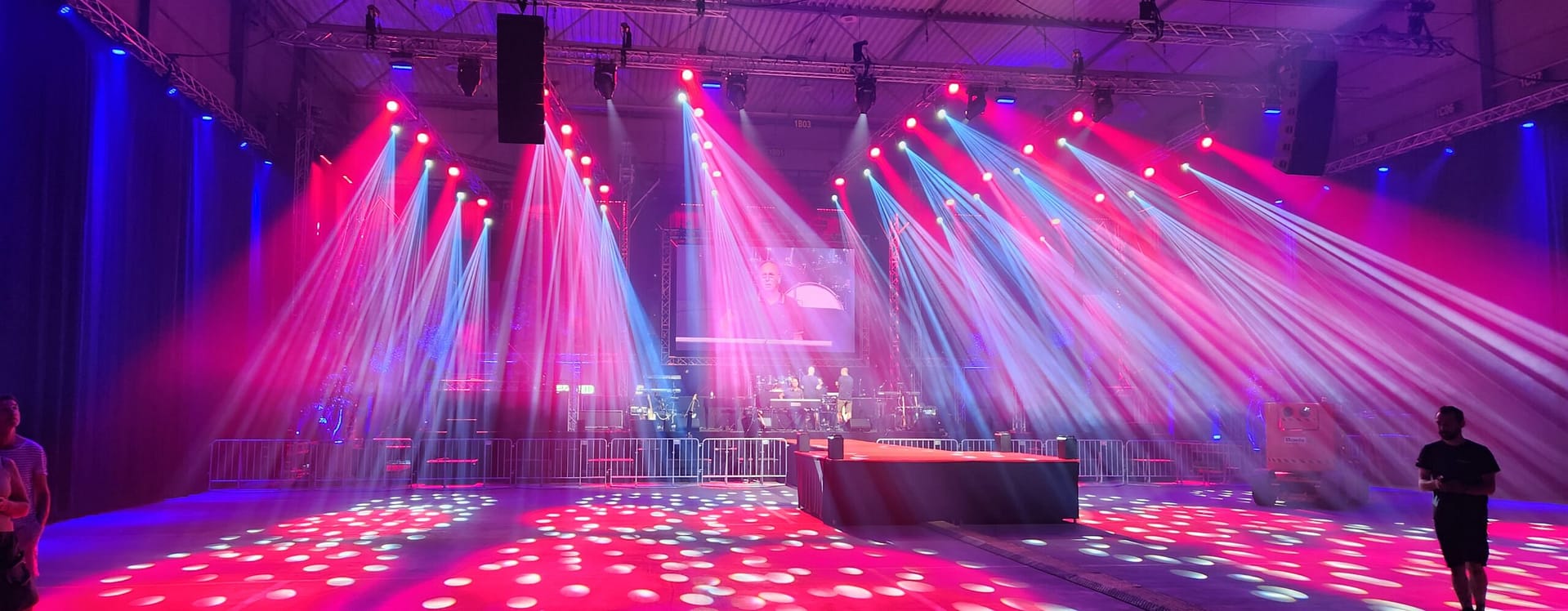 Podium met roze en blauwe lichtbundels tijdens een evenement