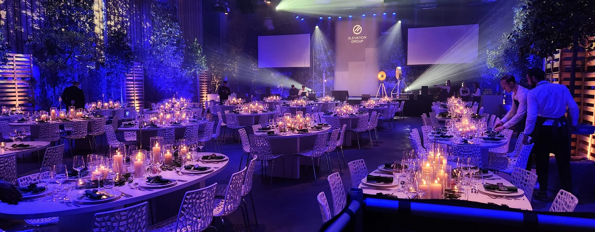 Feestelijke dinerzaal met podium, kaarslicht en audiovisuele techniek